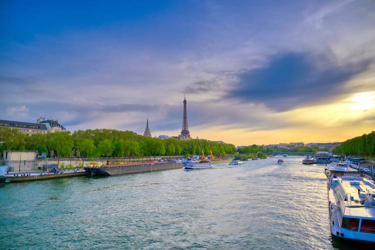 The brilliance of Paris from the Seine and its historical bridges. Sightseeing boat sailing on the Seine at sunset with the Eiffel Tower in the background.